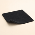 Black cut-to-fit activated-carbon pre-filter sheet with a trimmed sample on a warm eggshell background