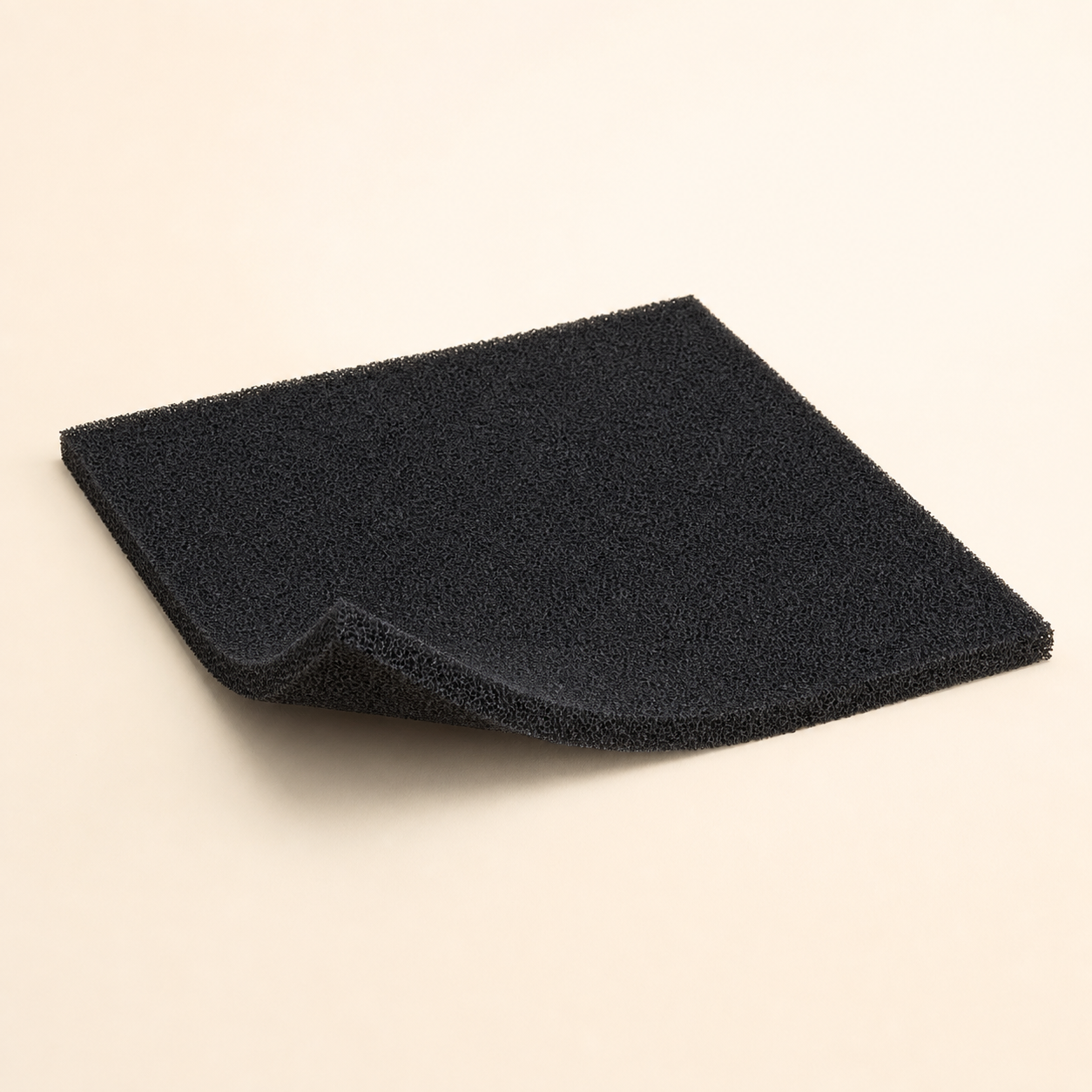 Black cut-to-fit activated-carbon pre-filter sheet with a trimmed sample on a warm eggshell background